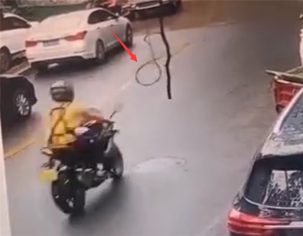 惊险！马路中间悬挂一根电缆 摩托车骑手经过刚好被套住脖子
