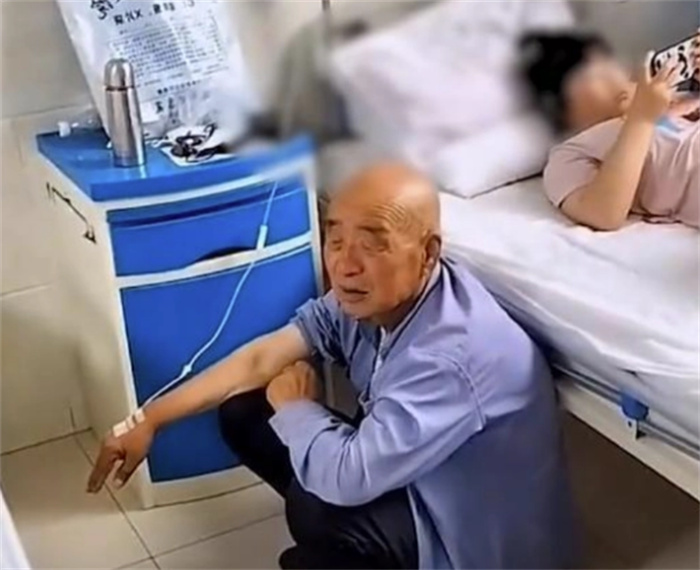 老人蹲在地上打点滴 孙女躺病床玩手机（溺爱孩子）